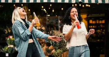 man in blue denim jacket holding clear drinking glass