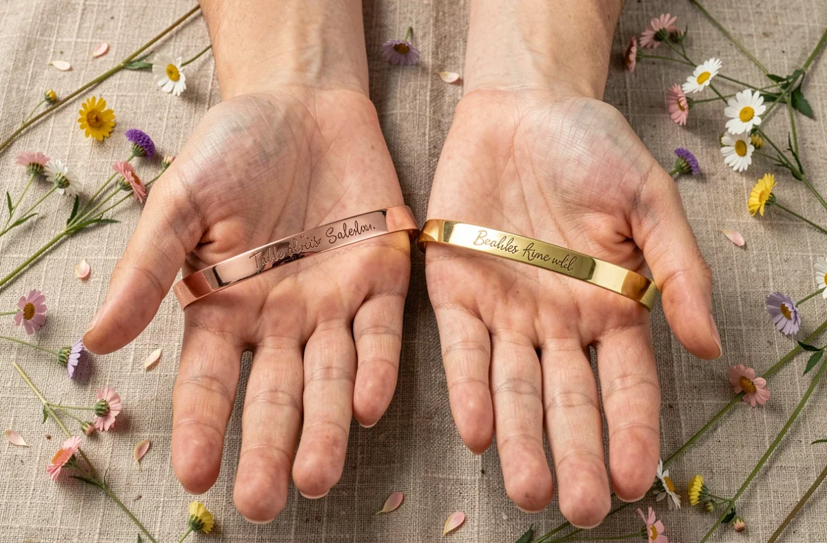 Deux joncs personnalisés en or rose et or jaune avec gravures manuscrites différentes portés côte à côte, tendance bijoux 2026